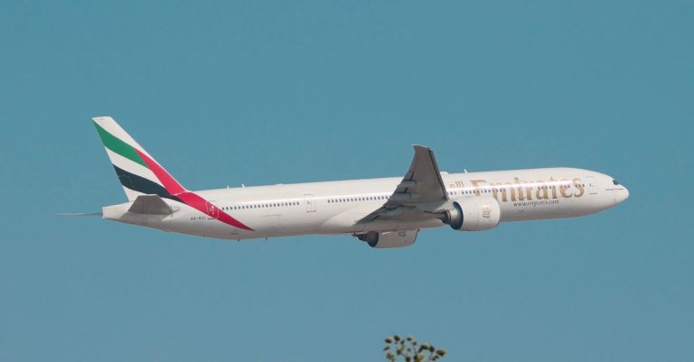 Emirates Boeing 777 in flight against a clear blue sky, illustrating Emirates launching cryptocurrency payments via Crypto.com Pay