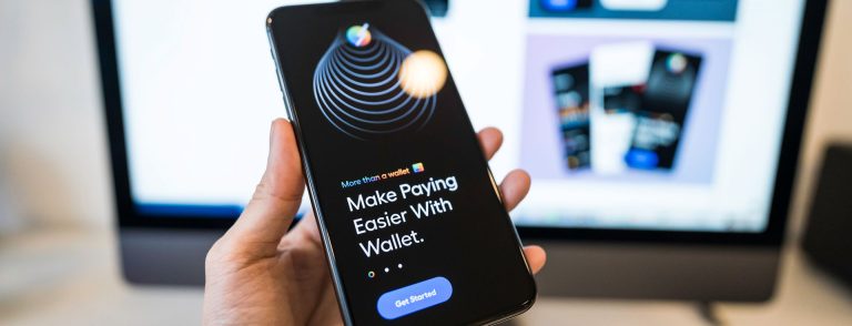 Hand holding a smartphone with a digital wallet app, illustrating Revolut's planned fintech launch in the UAE