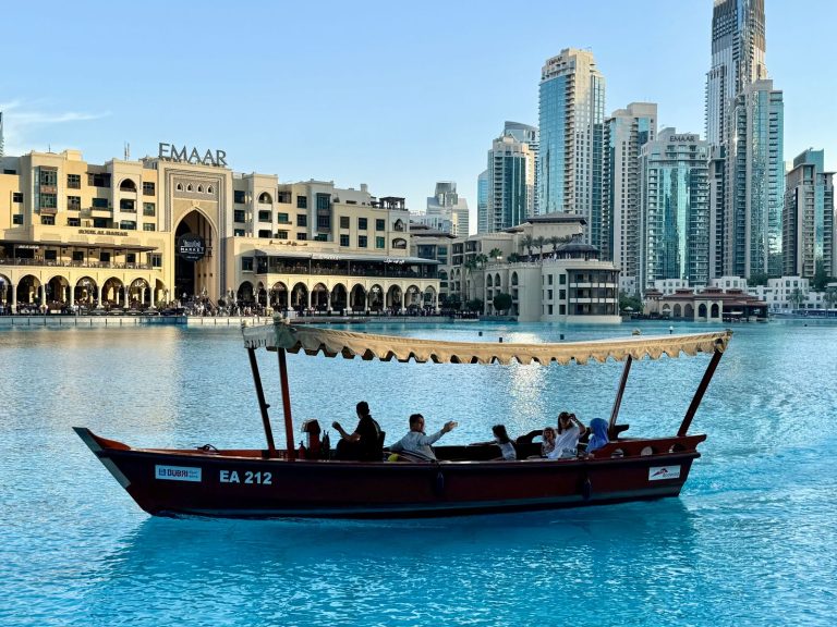 Guests ride a traditional abra boat past Downtown Dubai and the Dubai Fountain lake, illustrating the A Dubai Invite programme that reached 20,000 applicants and tripled capacity