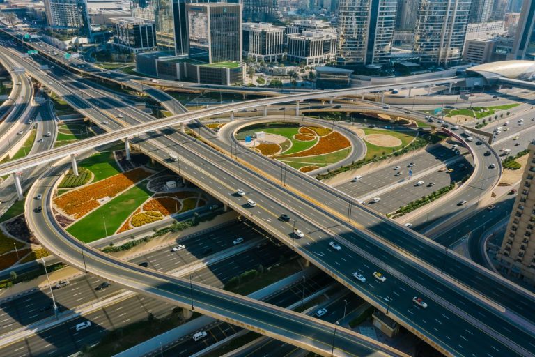 Aerial view of a multi-level Dubai highway interchange with bridges among skyscrapers, illustrating the new 500-metre bridge from Dubai World Trade Centre to Al Mustaqbal Street