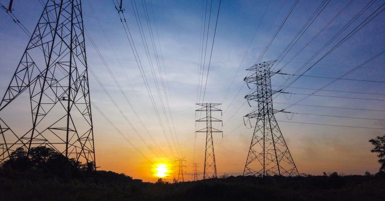 High-voltage power transmission towers at sunset, illustrating the UAE energy infrastructure behind TAQA H1 2026 results and AED 899 million dividend