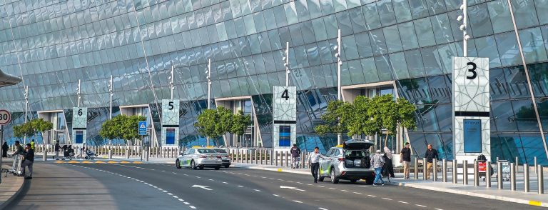Travellers and taxis at the departures kerbside of the Abu Dhabi airport terminal, illustrating the Etihad Airways and Etihad Rail agreement to integrate air and rail travel