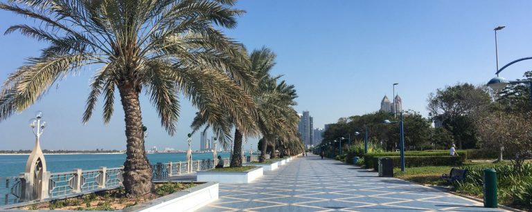 Palm-lined Corniche promenade in Abu Dhabi with the sea and city skyline, illustrating the liveability projects presented at LIVEX 2026