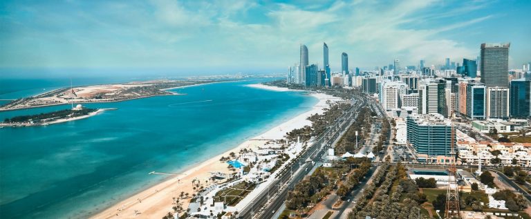 Aerial view of the Abu Dhabi Corniche with the city skyline, the beach and the turquoise water of the Gulf on a clear day