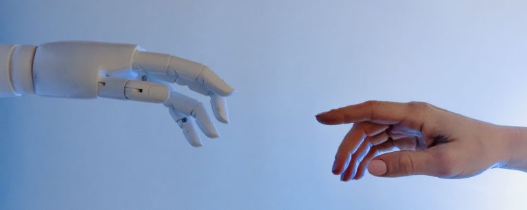 A robotic hand and a human hand reaching towards each other on a blue background