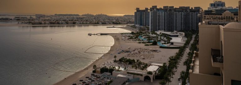 Waterfront residential buildings with a beach, swimming pools and a palm lined promenade in Dubai