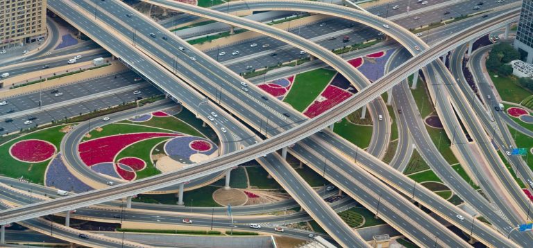 Aerial view of a multi level highway interchange in Dubai with bridges and ramps, illustrating the completed Oud Metha Road and Al Asayel Street development project