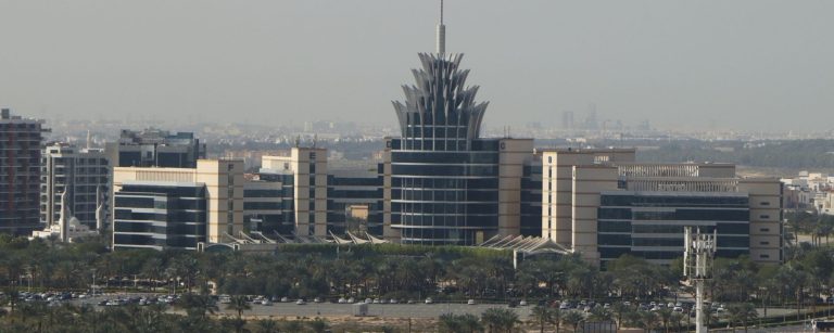 Dubai Silicon Oasis landmark office building with a crown-shaped top and spire, seen behind rows of palm trees