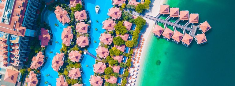 Aerial view of a beachfront resort in Dubai with lagoon pools, over the water villas and a beach lined with sun loungers, illustrating Gulf tourism worth USD 254 billion in 2025