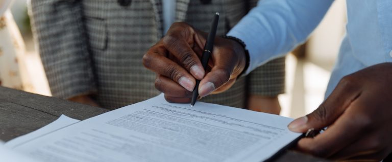Hand signing a legal document with a pen, illustrating the DMCC Foundations Regulations established in Dubai on 23 September 2026