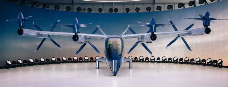 Electric vertical takeoff passenger aircraft with tilting rotors on a landing pad, illustrating the advanced air mobility sandbox planned by ARIDGE and Ras Al Khaimah in the UAE
