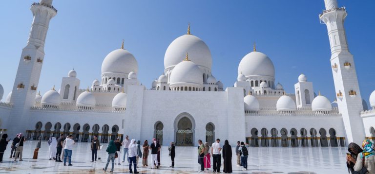 Visitors in the courtyard of the Sheikh Zayed Grand Mosque in Abu Dhabi, illustrating the AED 251.3 billion contribution of travel and tourism to the UAE economy in 2025