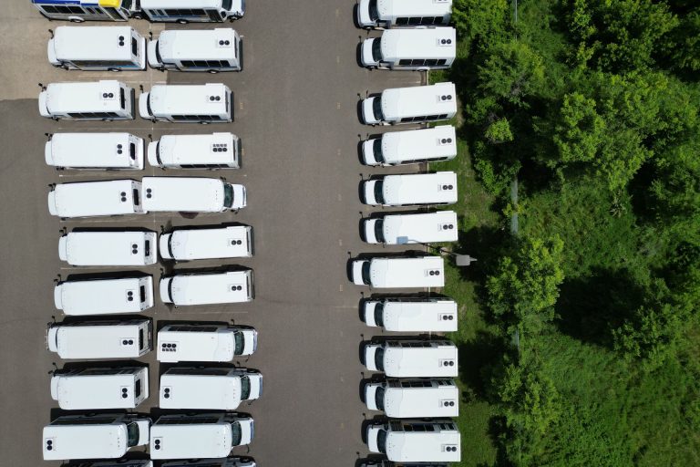 Aerial view of white buses parked in rows at a depot, illustrating real-time fleet management for Abu Dhabi public buses