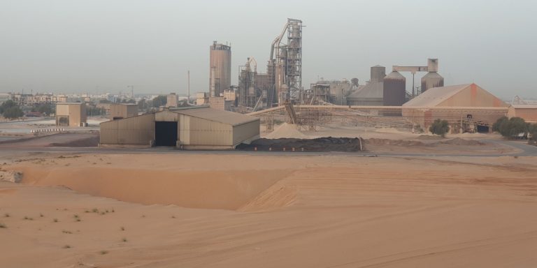 Industrial plant and warehouse behind a levelled sandy plot in the desert, illustrating development-ready industrial land in the Musaffah Innovation District, Abu Dhabi