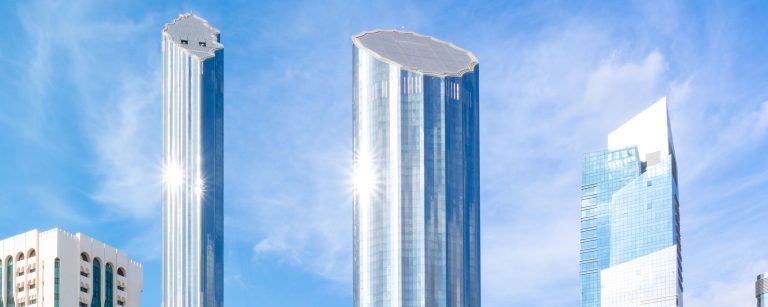 Glass office towers in Abu Dhabi against a blue sky, illustrating UAE bank lending growth in August 2026