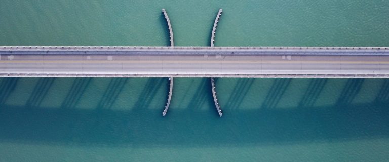 Aerial view of a road bridge over turquoise sea water, illustrating the AED 872 million seven-bridge network linking Ramhan and Jubail Islands to the E12 in Abu Dhabi