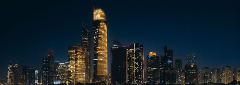 Abu Dhabi skyline at night with illuminated office and residential towers