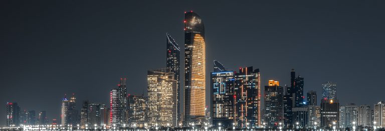 Abu Dhabi skyline at night with illuminated towers along the waterfront