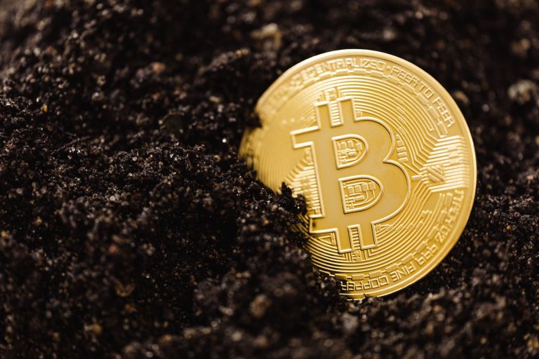 Gold Bitcoin coin half buried in soil, illustrating the ADGM guidance on crypto mining activities published on 28 October 2026
