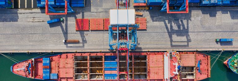 Aerial view of a cargo ship at a container terminal quay, illustrating UAE-EAEU trade in goods