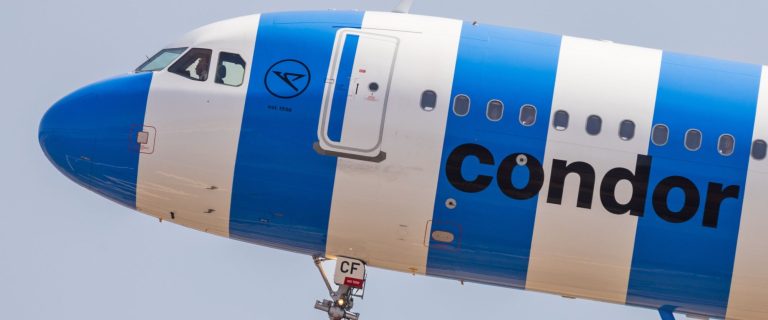 Condor airliner in blue and white stripes in flight, close-up of the nose, cockpit and Condor logo