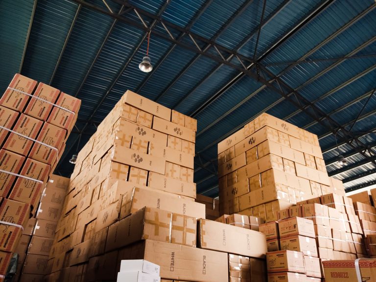 Tall stacks of parcel boxes in a warehouse, illustrating the Dubai CommerCity Phase Two expansion and The Hive vertical logistics facility