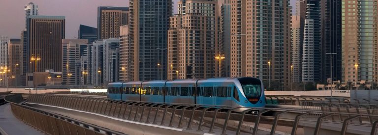 Dubai Metro train on the elevated track in front of Dubai Marina towers at dusk