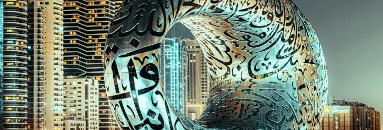 The Museum of the Future in Dubai with Arabic calligraphy on its steel facade, lit at night among high-rise towers