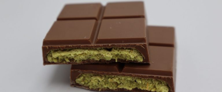 Milk chocolate bar broken in two with a green pistachio filling