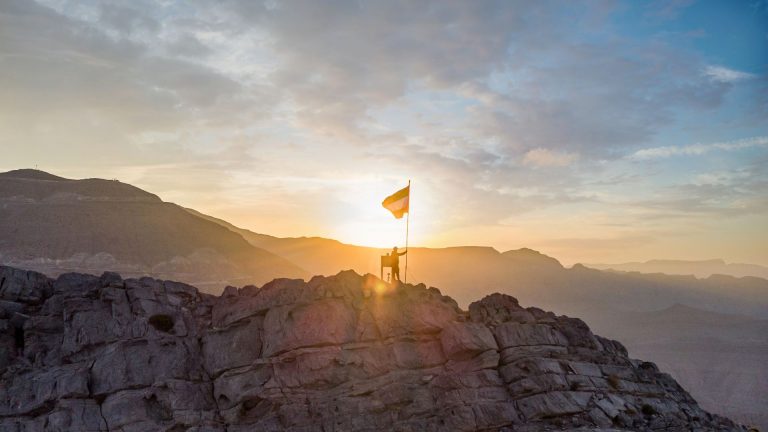 UAE flag on a mountain peak at sunrise in Ras Al Khaimah, illustrating Fitch affirming the emirate at A+