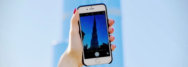 Hand holding a smartphone with the Burj Khalifa on screen, illustrating digital government services in the UAE